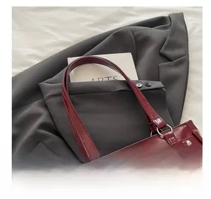 Detail of dark red bag with lace bow decoration and silver rivets on faux leather