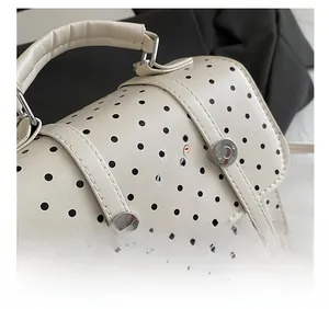 Detailed close-up of cream polka dot handbag featuring hamburger graphic and metallic buckles