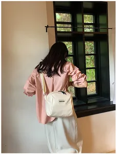 Lifestyle view of a white PU leather crossbody makeup bag with a minimalist logo strap