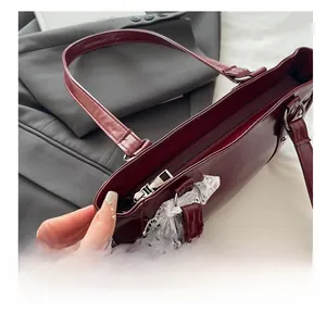 Detailed close-up of smooth metal zipper and white lace trim on dark red handbag