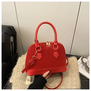 Close-up of red shell-shaped handbag with leopard embossing and gold hardware details