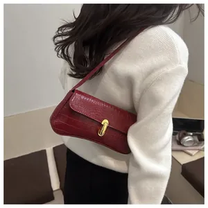 Detail shot of wine red crocodile embossed shoulder bag with gold horseshoe buckle closure