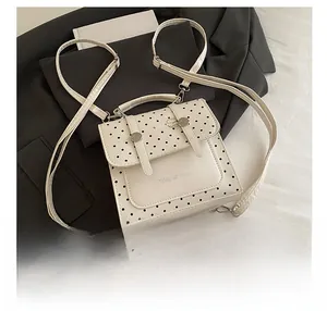 Detail view of cream-colored polka dot mini backpack with Tidal Dryness lettering