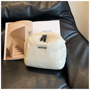 Detail of a creamy white waterproof PU leather makeup bag with dual black zippers on a sofa