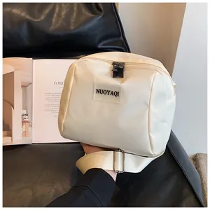 Close-up of off-white nylon crossbody bag with black logo tag and adjustable wide strap