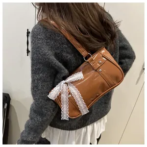 Detail of a brown leather shoulder bag featuring an elegant white lace bow decoration