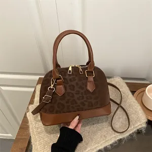 Minimalist brown shell-shaped crossbody bag with leopard print detail and gold zipper