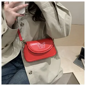 Macro shot of red crossbody bag with white butterfly embroidery and gold metal hardware