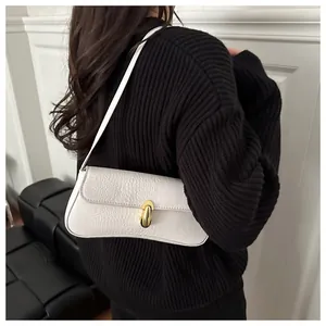 Detail view of white crocodile pattern underarm bag with gold oval clasp on black sweater