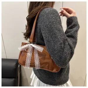 Detailed view of a brown vintage shoulder bag featuring a white lace bow and leather strap