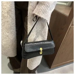 Detail of black embossed faux crocodile leather shoulder bag with golden metal clasp