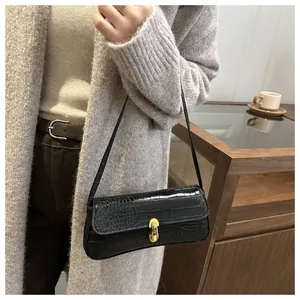 Detailed view of black crocodile pattern underarm bag with gold U-shaped metal buckle