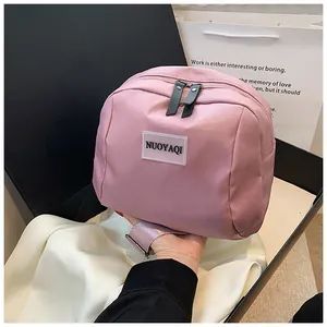 Detailed view of pink nylon shoulder bag featuring dual zippers and branded logo patch