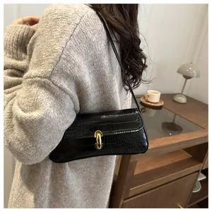 Detailed view of black crocodile pattern baguette bag with stylish gold U-shaped metal lock