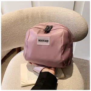 Detail of a dusty pink travel pouch with a transparent brand tag and double zipper closure