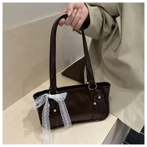 Detail of coffee brown glossy faux leather bag with white lace ribbon and silver rivets