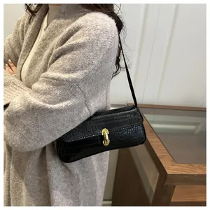 Detailed view of black crocodile pattern baguette bag with a gold metal twist lock buckle