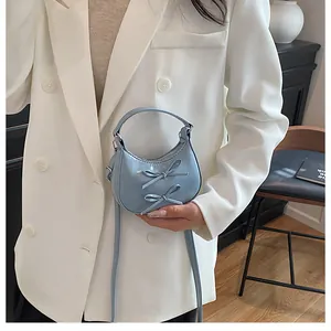 Detail of light blue patent leather bag with double bows and detachable strap