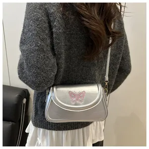 Silver shoulder bag with pink butterfly embroidery worn by model from a side back view