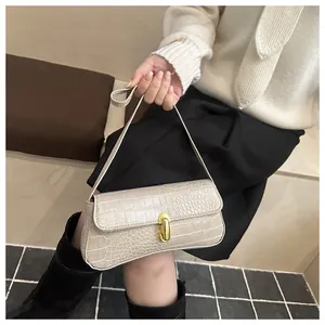 Close-up of cream faux crocodile texture and shiny gold lock on underarm bag