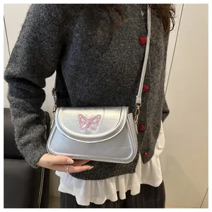 Détail d'un sac argenté métallisé avec broderie papillon rose et fermoir doré
