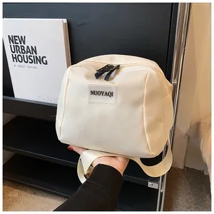 Detail of beige nylon crossbody bag with black dual zippers and wide woven strap
