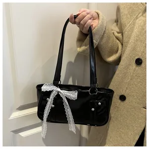Close-up of black leather pillow bag with white lace bow and silver rivet details