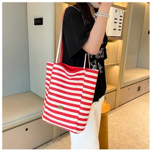 Detail showing red and white striped canvas tote bag with metal logo on a model