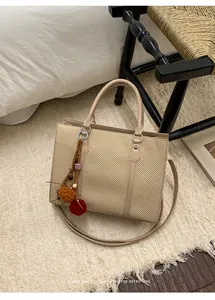 Detail of woven texture handbag with leather straps and retro tassel charm on carpet
