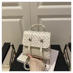 Detailed close-up of white faux leather backpack with black polka dots and silver metal buckle
