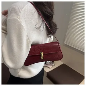 Detail view of dark red crocodile embossed shoulder bag with golden metal buckle clasp