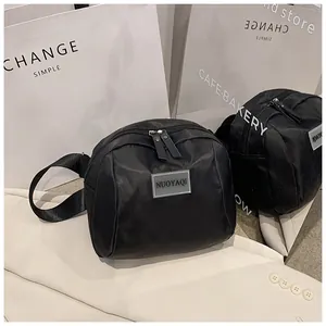 Close-up of black nylon crossbody bag with logo patch and durable zipper details