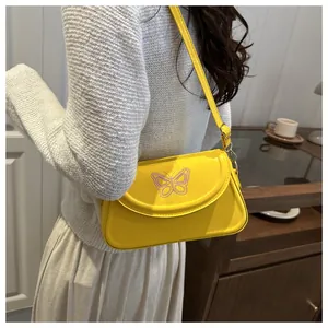 Detail of yellow shoulder bag with purple butterfly embroidery on lifestyle model
