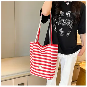 Detailed shot of a red and white striped canvas tote bag worn by a female model