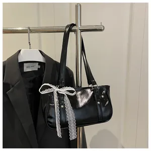 Detail of a black glossy bag with silver studs and a white lace bow on a metal hanger