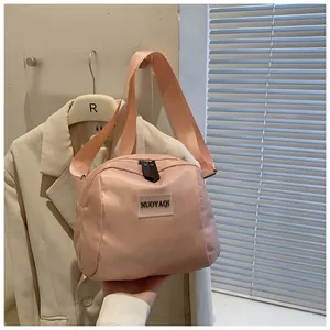 Pink nylon crossbody dumpling bag with smooth zipper detail and stylish wide shoulder strap