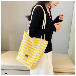 Detail of yellow and white striped canvas tote bag with handmade leather patch detail
