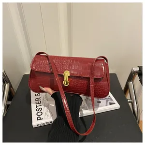 Detail of dark red crocodile embossed faux leather underarm bag with gold metal buckle