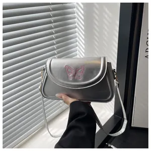 Detailed view of silver shoulder bag featuring pink butterfly embroidery and sleek strap
