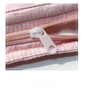 Close-up of pink quilted tote bag showing the smooth zipper detail and heart pattern