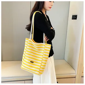 Detail of yellow and white striped canvas tote bag with shoulder straps and interior lining