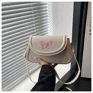 Detail of cream shoulder bag with pink butterfly embroidery and gold metal hardware