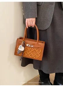 Detail of caramel leather bag featuring quilted embroidery and metal clasp