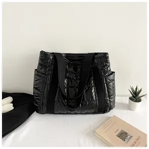 Détail du sac fourre-tout noir matelassé brillant avec anses larges et poche latérale