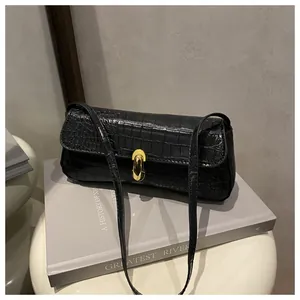 Close-up of black crocodile pattern leather and gold metal buckle on shoulder bag