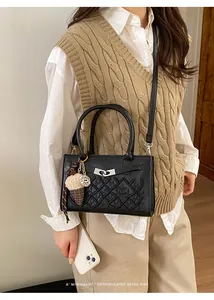 Detail of black glossy leather crossbody bag with diamond quilting and silver twist lock