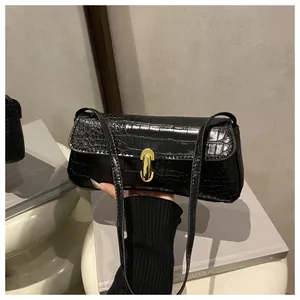 Close-up of black crocodile pattern faux leather bag with gold oval rotating metal lock
