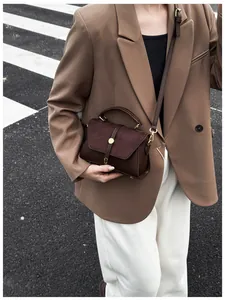 Nahaufnahme einer Vintage dunkelbraunen Leder- und Wildleder-Mini-Tasche mit Golddekor