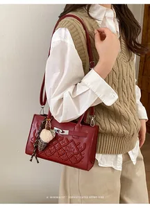 Detail of burgundy leather crossbody bag with diamond embroidery and plush charm