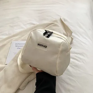 White puffy nylon crossbody bag with minimalist brand label and durable black zippers